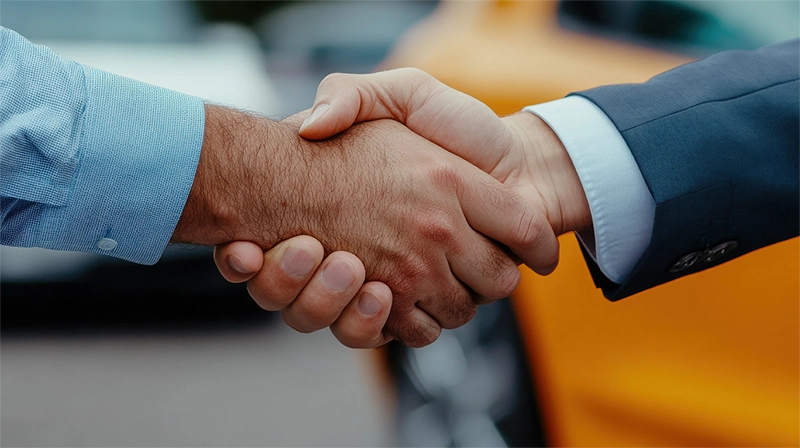 image of two people shaking hands near cars