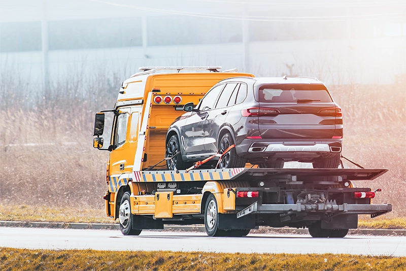 photo of an orange tow truck driving away with a towed SUV